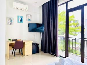 a bedroom with a desk and a tv and a window at Sunrise Homestay in Danang