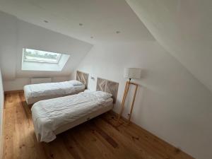a white room with two beds and a window at la maison des souvenirs précieux in Surtainville