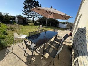 a table and chairs with an umbrella and an outdoor table and chairs at la maison des souvenirs précieux in Surtainville +14 photos