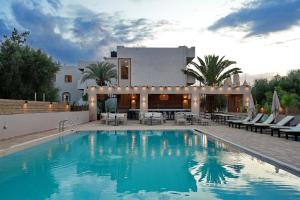 a swimming pool in front of a house at PEARL BOUTIQUE Hotel BEACH ROAD MALIA in Malia