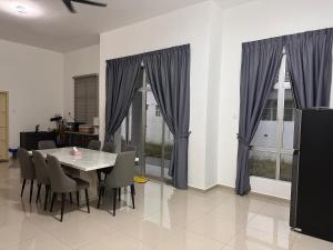 a dining room with a table and chairs and windows at Xiang Homestay in Padang Serai