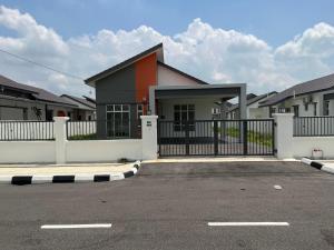 a house with a black fence and some houses at Xiang Homestay in Padang Serai