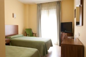 a hotel room with two beds and a television at Hotel Hidalgo Quijada in Alcazar de San Juan