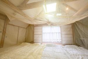 a bedroom with a large white bed with a window at ココロとカラダの陽転スポット～八甲田アマテラスリトリート in Aomori