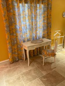un tavolo e una sedia in una stanza con tende di Chambre d'Hôte Couguiolet - avec piscine a Foissac