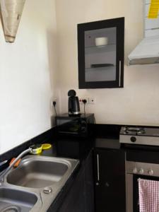 una cocina con fregadero y estufa en Diani Fisherhut Studio, en Diani Beach 19 fotos más