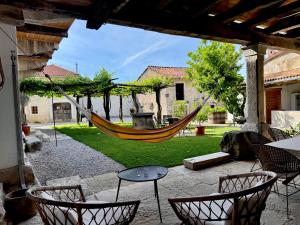a hammock in a patio with a table and chairs at Vila Kobdilj 1835 Historic Homestead with Shared Courtyard in Štanjel