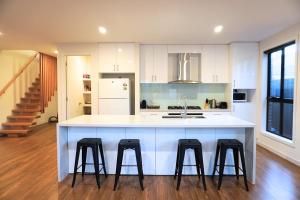 a kitchen with a white counter and four stools at Brand New Home with Private Rooms in Tottenham