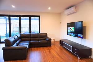 a living room with a leather couch and a flat screen tv at Brand New Home with Private Rooms in Tottenham