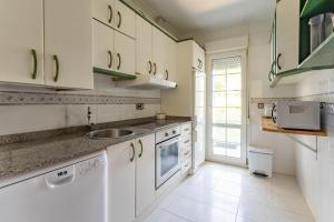 a kitchen with white cabinets and a sink at Tus vacaciones en Liencres in Liencres +6 photos
