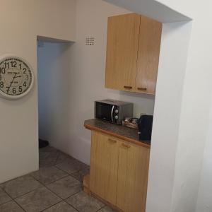 una cocina con microondas y un reloj en una encimera en Linga Longa, en Beaufort West