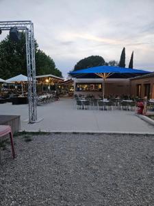 a patio with tables and chairs with blue umbrellas at mobil-home 6 personnes chez maylia in Cadenet +32 photos