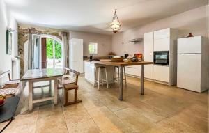 a kitchen with a table and a white refrigerator at Maison Piscine Proche Arles in Tarascon