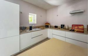 a kitchen with white cabinets and a sink and a window at Maison Piscine Proche Arles in Tarascon