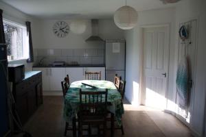 a kitchen with a table and chairs and a clock on the wall at Woodland Lodge in London +14 photos