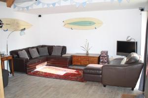 a living room with a leather couch and a tv at Woodland Lodge in London