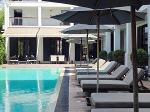 a row of lounge chairs and umbrellas next to a swimming pool at Buri Siri Boutique Hotel in Chiang Mai