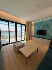 a living room with a couch and a table and a television at LA Brisa Durrat Alarous شاليهات لابريزا درة العروس شاطئ البرادايس للعوائل فقط in Durat Alarous