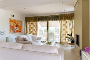 a living room with two white couches and a television at La Casa Rosa Seaside Getaway in Marathiás