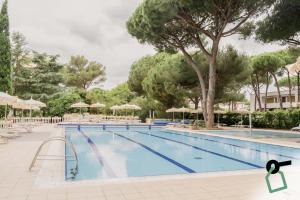 a large swimming pool with chairs and umbrellas at Hotiday Marina di Bibbona in Marina di Bibbona