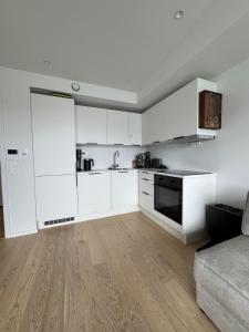 a white kitchen with white cabinets and a couch at Wonderful apartment in centrum in Tromsø