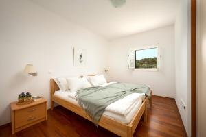 a white bedroom with a bed and a window at Sun Spalato Maslinica in Maslinica