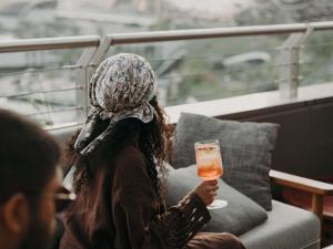a woman sitting on a couch holding a glass of beer at 25hours Hotel Dubai One Central in Dubai