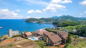 a house on a hill next to a body of water at Geojedo Pilos Ocean View Pension in Geoje 