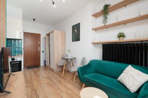 a living room with a green couch and a table at Piotrkowska Sunset Apartment in Łódź