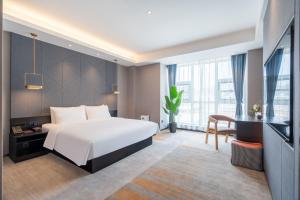 a hotel room with a bed and a desk at 沃德酒店滕州市政府火车站店 in Tengzhou