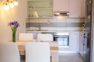 una cucina con tavolo e una cucina con armadietti bianchi di Apartments Iva a Krk