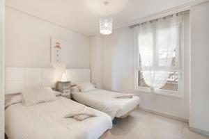 two beds in a white room with a window at Apartamento en Isla Canela in Ayamonte +17 photos