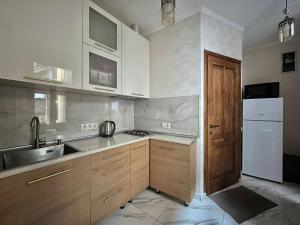 a kitchen with wooden cabinets and a white refrigerator at Apartment near Rustaveli theatre in Stantsiya Mukhiani
