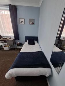 a bedroom with a bed with a blue wall at Westbrook Lodge Guest House in Margate
