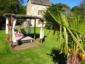 a wooden gazebo with a bench and a table at La maison de Gilbert Jacuzzi Piscine chauffée in Chaudes-Aigues