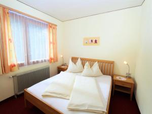 sypialnia z łóżkiem z białymi prześcieradłami i poduszkami w obiekcie Sunlit Cabin with Jacuzzi in Turracherhohe w mieście Turracher Hohe