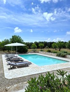 een zwembad met ligstoelen en een parasol bij Trullo Tranquillo Ostuni in Ostuni