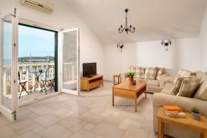 a living room with a couch and a tv and a balcony at Sun Spalato Maslinica in Maslinica