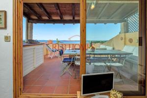 a room with a balcony with a tv and a table at Marineledda la terrazza sul golfo in Marinella