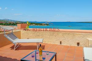 a patio with a table and a chair and the ocean at Marineledda la terrazza sul golfo in Marinella