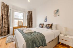 a bedroom with a large white bed and a window at Gorgeous 2BR plus Victorian home with Parking and Garden in London