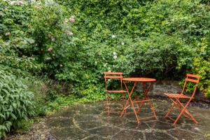 two chairs and a table in front of a hedge at Gorgeous 2BR plus Victorian home with Parking and Garden in London