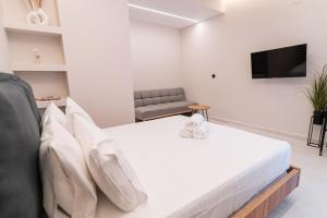 um quarto com uma cama branca e uma televisão em Center Holiday em Preveza