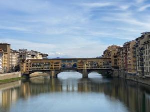 a bridge over a river in a city with buildings at Fashion Florence Rooms in Florence