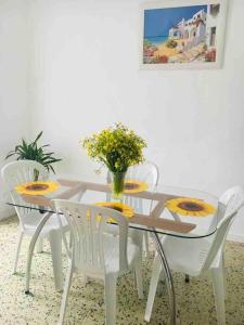 una mesa de comedor con sillas blancas y un jarrón de flores en Paderne Village House, en Paderne