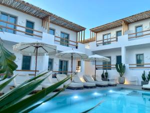 a villa with a swimming pool and chairs and umbrellas at Mykonos Dot Suites in Ano Mera