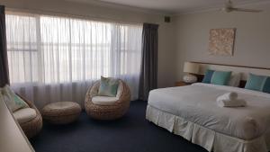 a bedroom with a bed and chairs and a window at Villa Riviera on River Front in Ballina