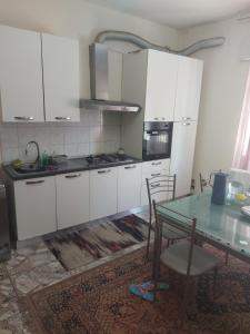 a kitchen with white cabinets and a table with chairs at Ever Green in Mestre