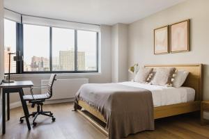 a bedroom with a bed and a desk and windows at Blueground Upper East Side AC wd nr parks NYC-1635 in New York