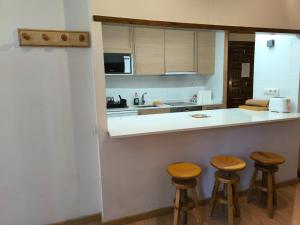a kitchen with three bar stools and a counter at Ibón de Piniecho in Formigal